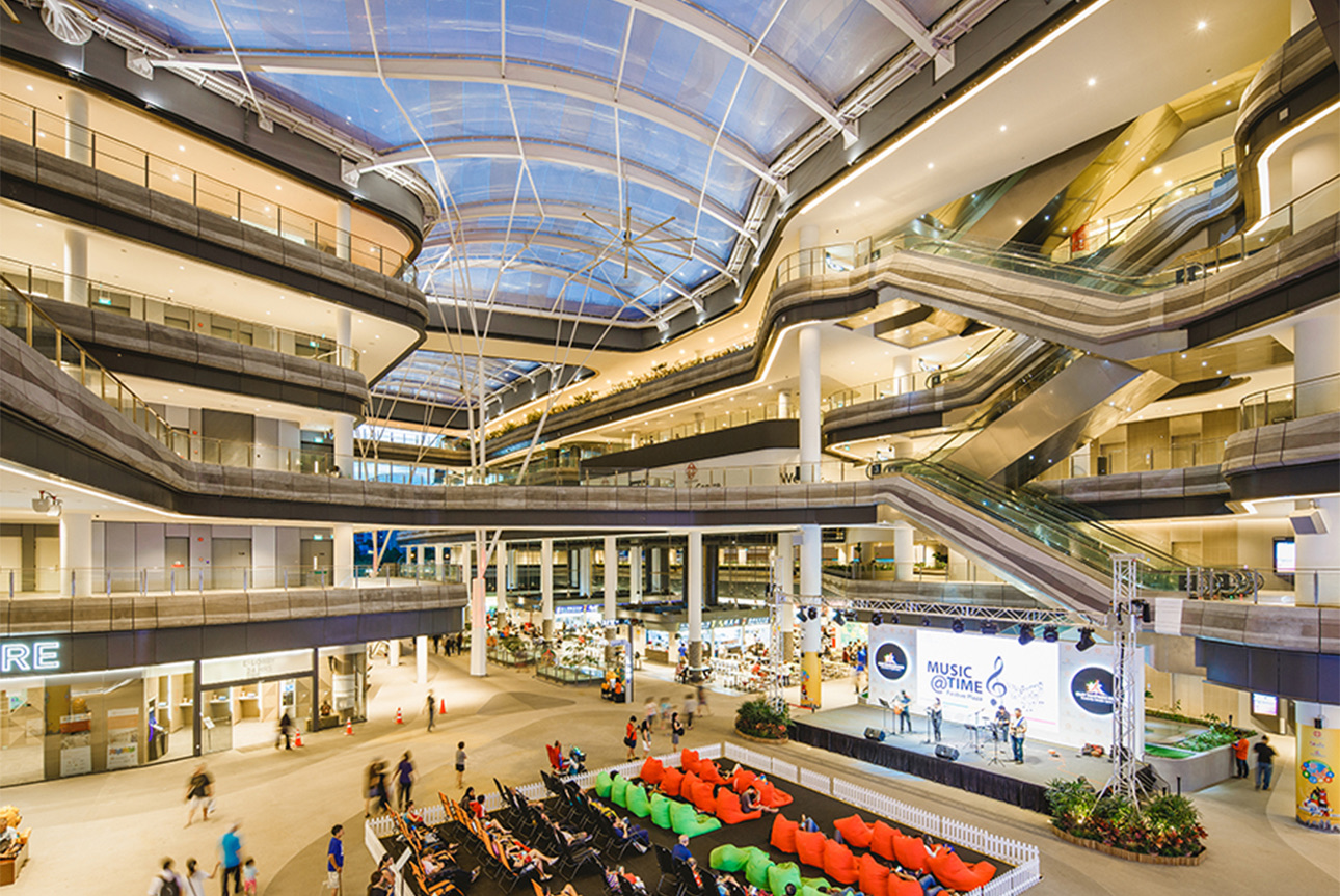 Festive Plaza atrium at Our Tampines Hub, with a live stage, bean bags, and the glass roof